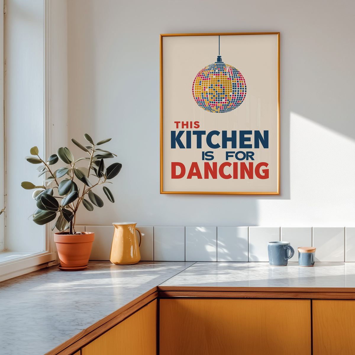 Kitchen Is For Dancing blue disco print shown in a gold frame above a marble counter in a tan kitchen