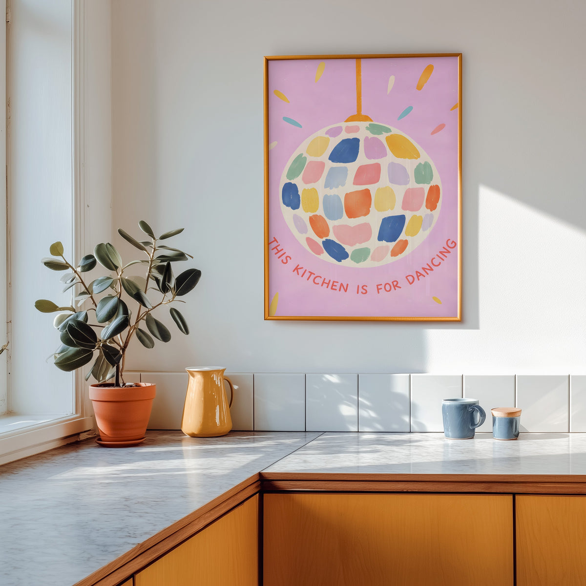 Pastel disco ball print in a gold frame above a marble counter with a yellow jug