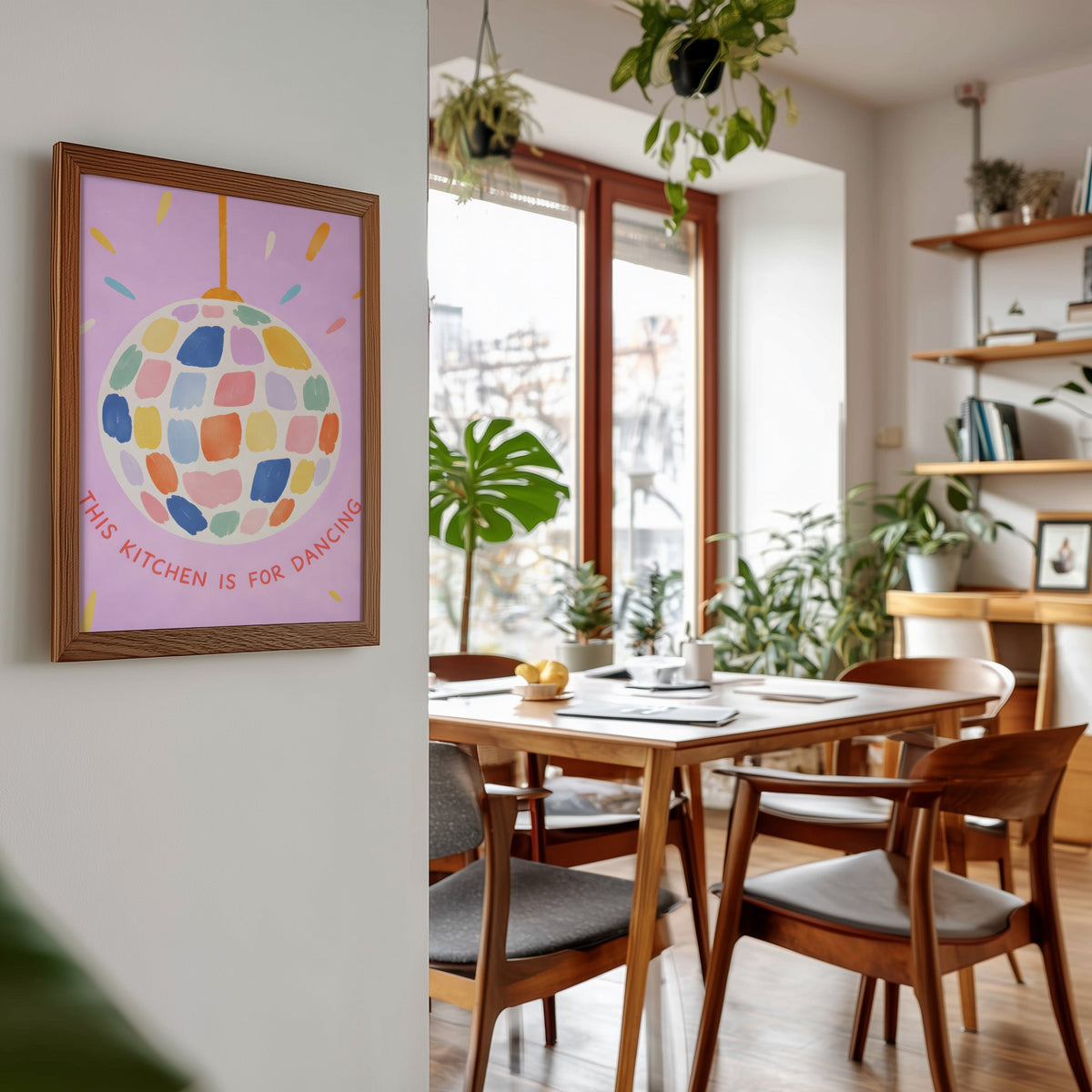 Pastel disco ball print in a walnut frame beside a mid-century dining table