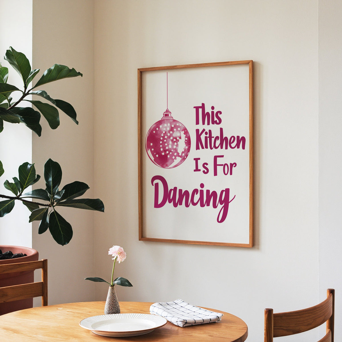 Kitchen Is For Dancing pink script print in a walnut frame above a round table beside a fiddle-leaf fig