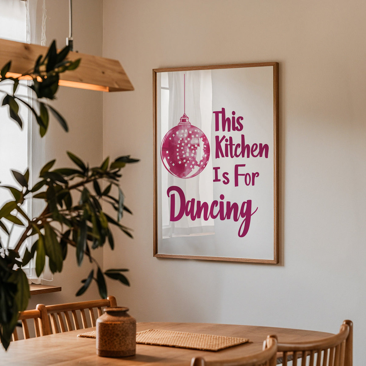 Kitchen Is For Dancing pink script print in a walnut frame above a dining table with olive branches
