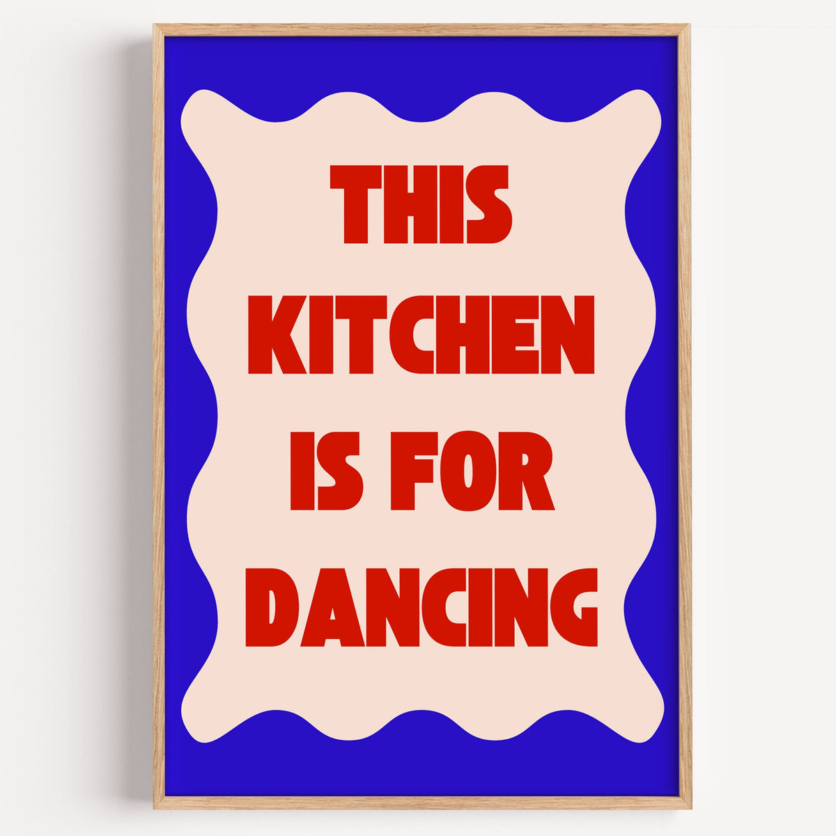 Kitchen Is for Dancing wavy blue print in a light oak frame on a plain white wall