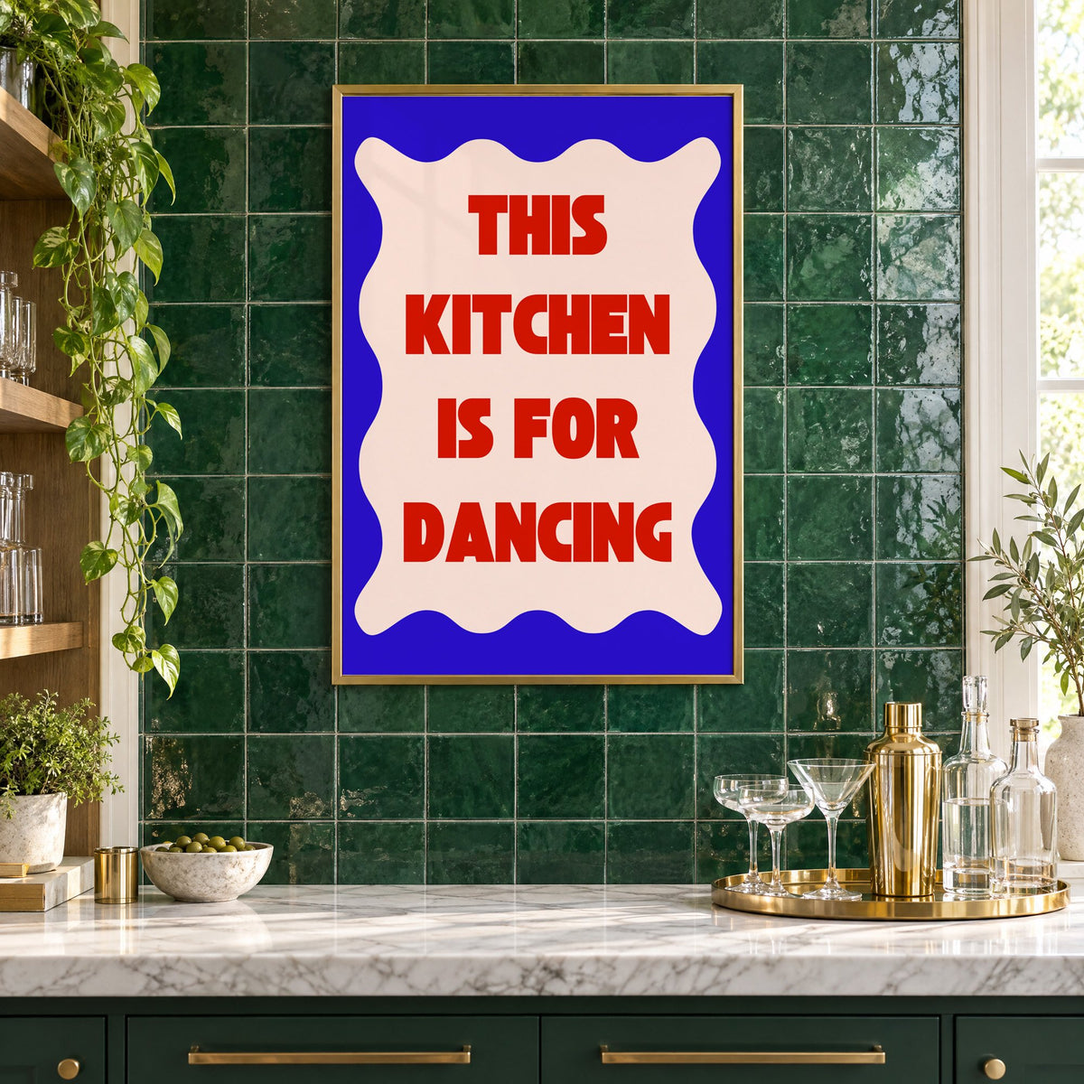 Kitchen Is for Dancing wavy blue print in a brass frame on emerald green tiles above a home bar with coupe glasses
