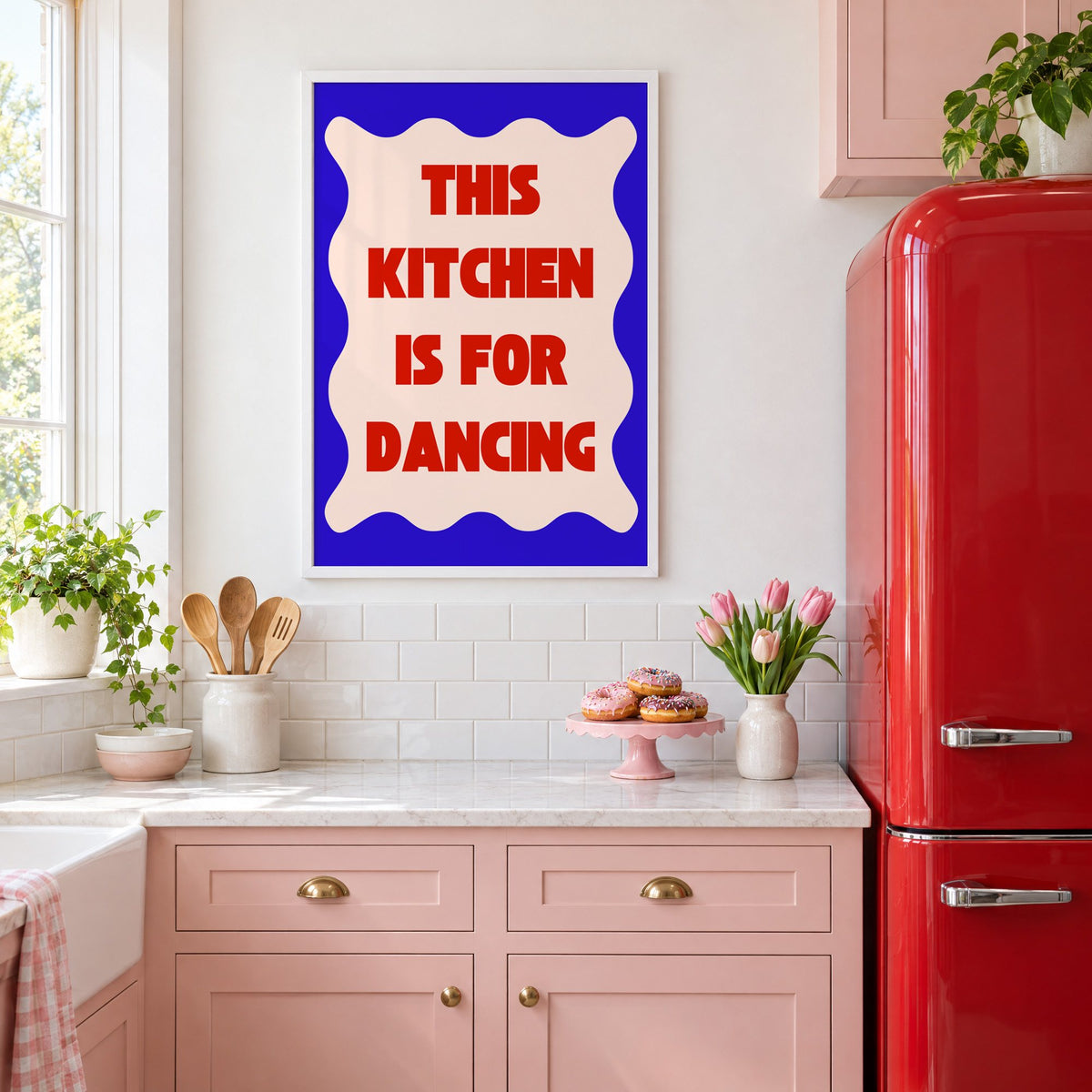 Kitchen Is for Dancing wavy blue print in a white frame in a pink kitchen beside a red retro fridge