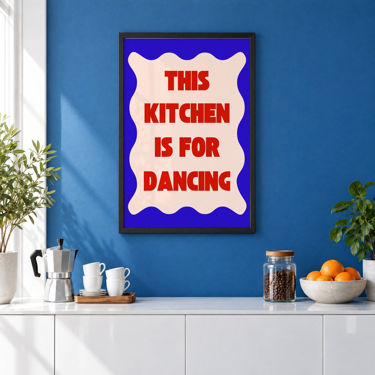 Kitchen Is for Dancing wavy blue print in a black frame on a cobalt blue wall above a coffee station