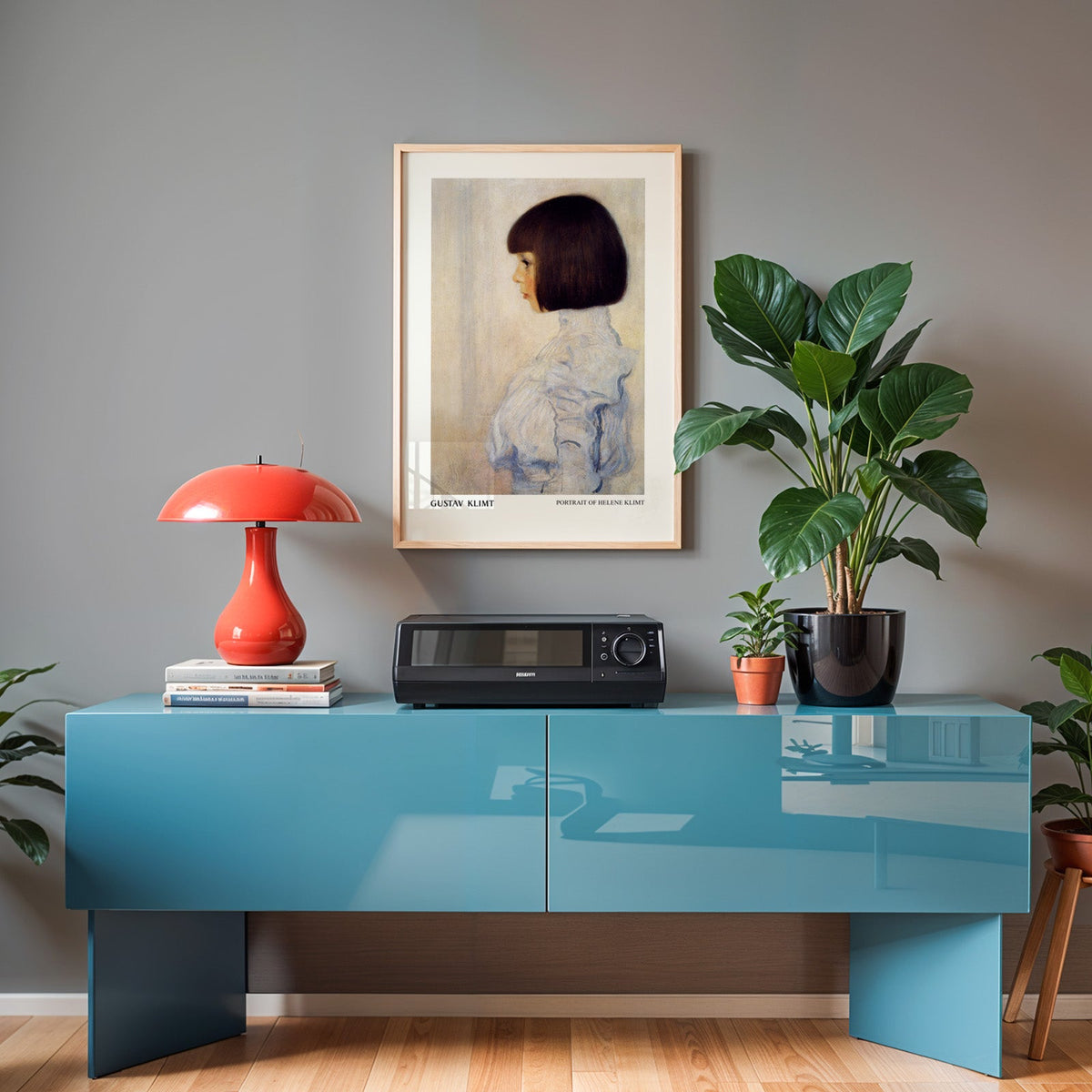 Gustav Klimt poster in an oak frame above a teal sideboard with a red lamp