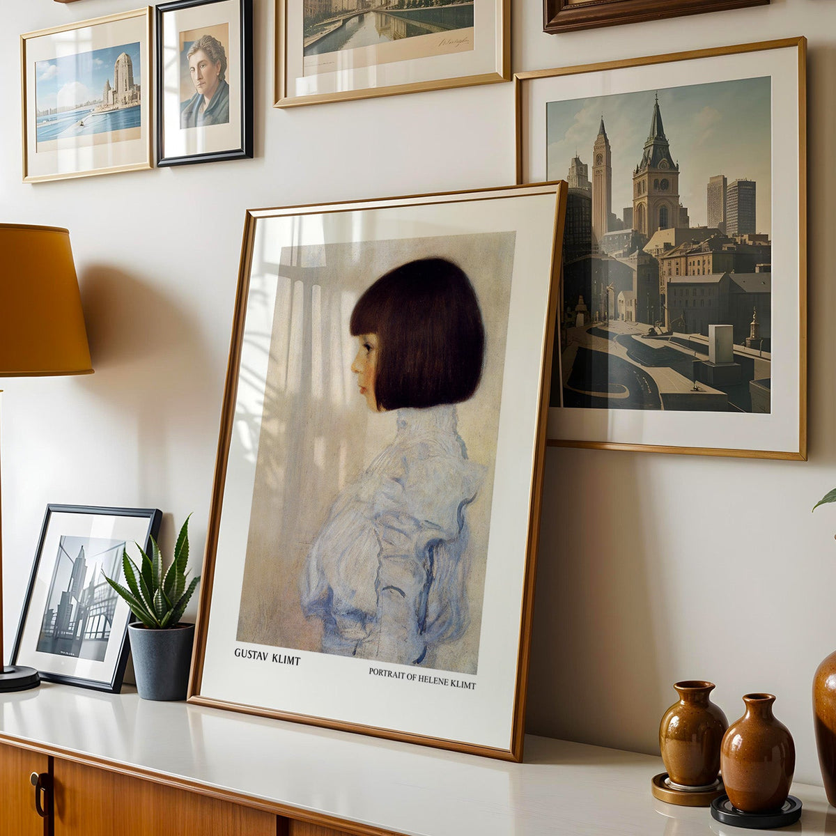 Klimt print shown in a gold frame leaning on a sideboard in a gallery wall