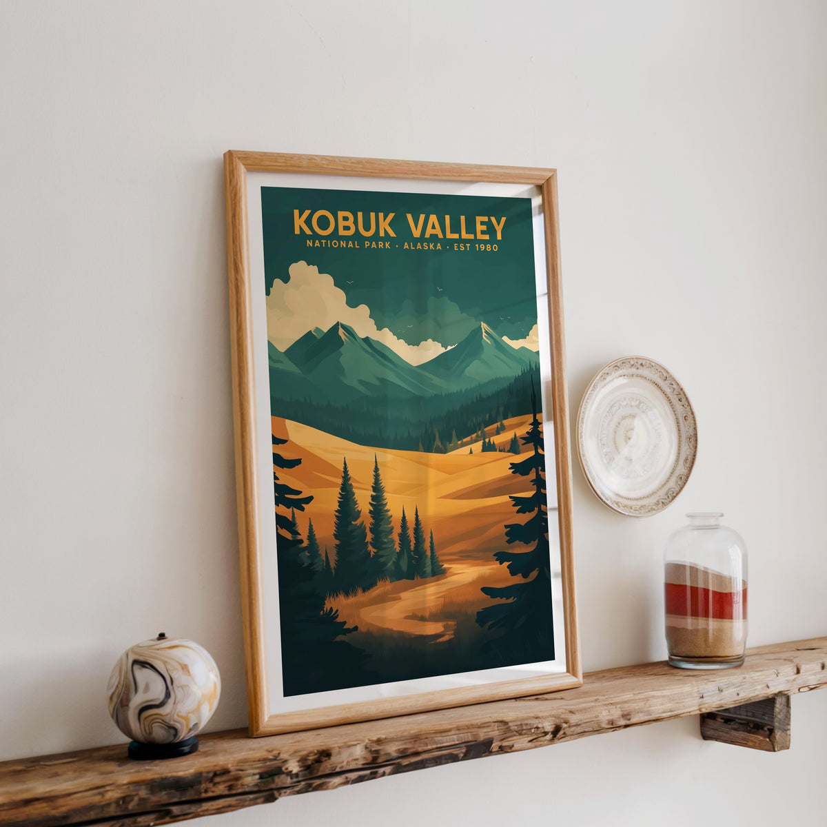 Kobuk Valley National Park print in an oak frame on a wood shelf with ceramics and a sand-filled jar