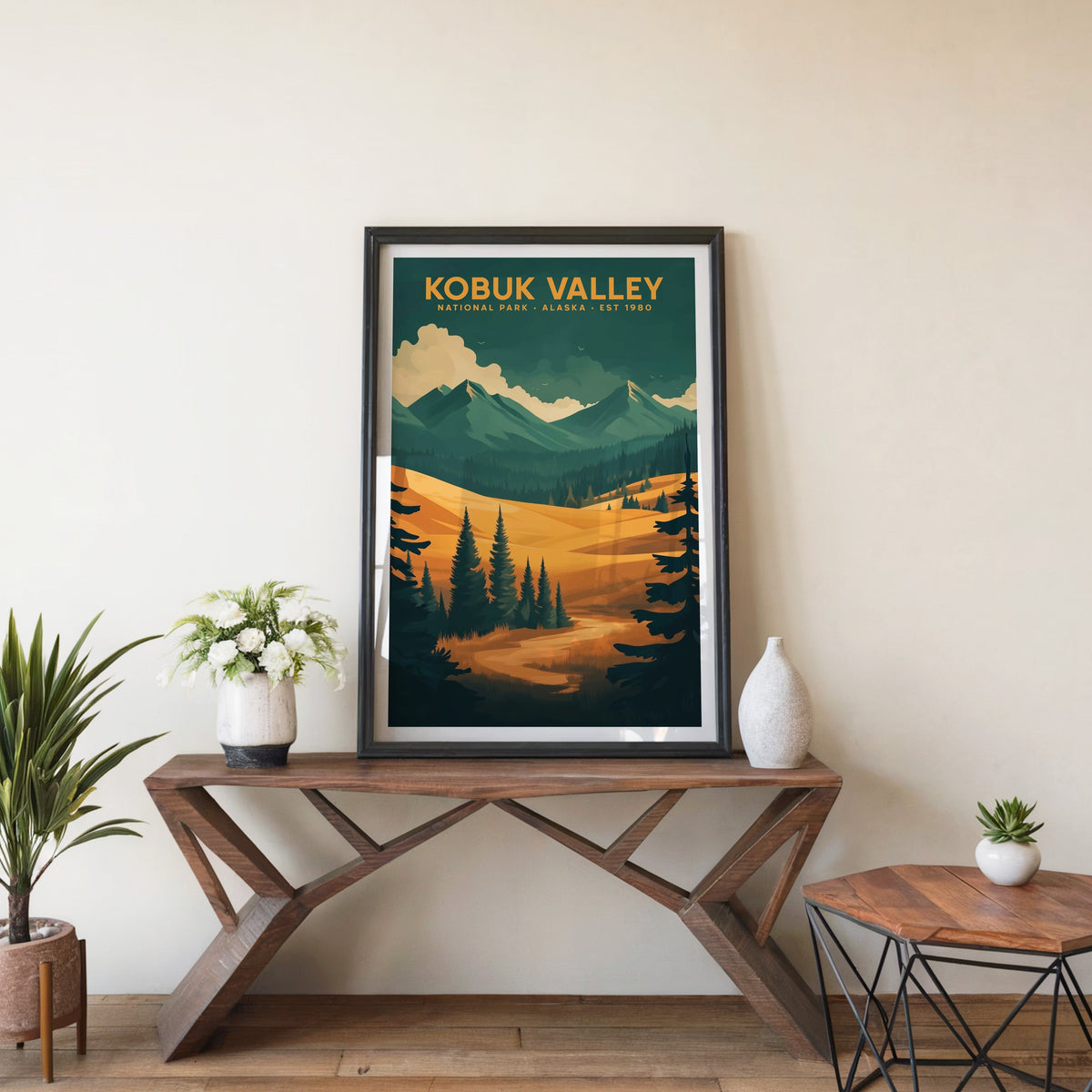 Kobuk Valley poster in a black frame on an entryway console table beside white flowers and a yucca