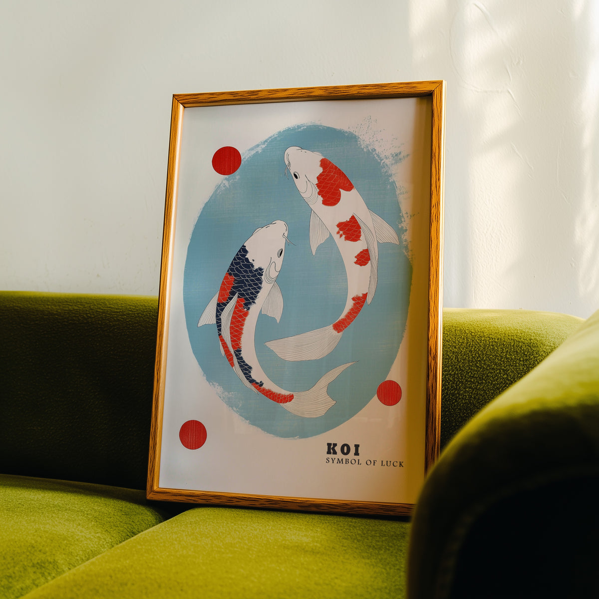 Two koi circling in blue oval print in an oak frame propped on a green velvet sofa