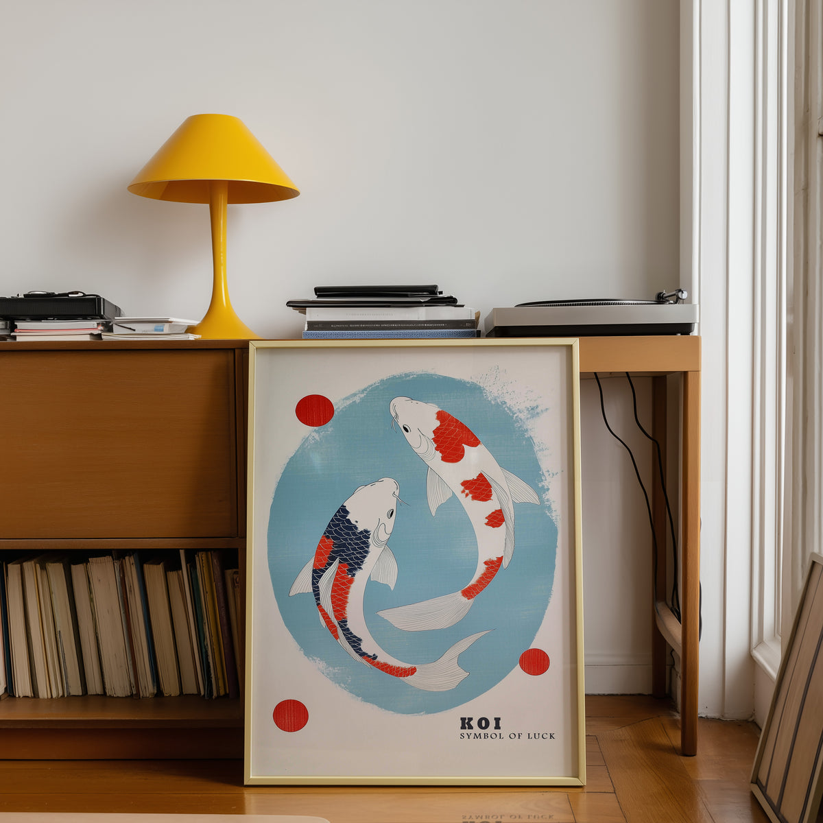 Two koi circling in blue oval print shown in a gold frame below a teak desk with a yellow lamp
