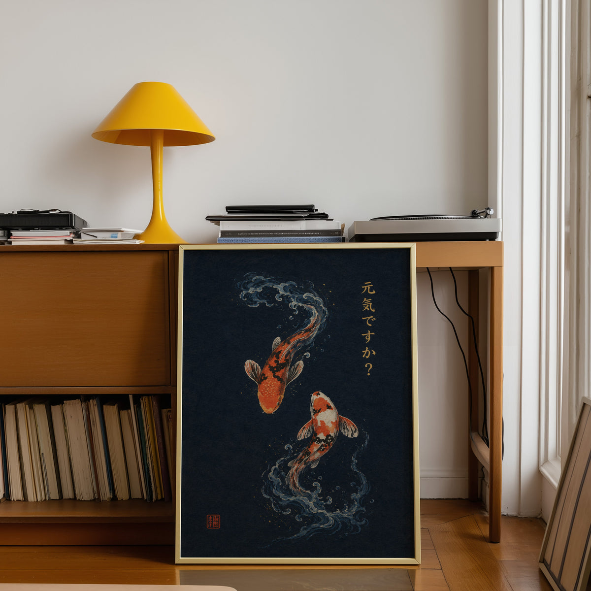two koi fish on navy print shown in a gold frame leaning under a teak desk with a yellow lamp
