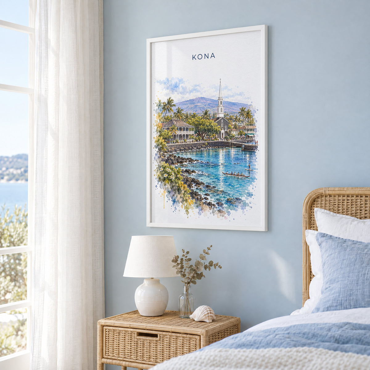 Kona, Hawaii watercolor print in a white frame on a pale blue wall beside a rattan bed in a coastal bedroom
