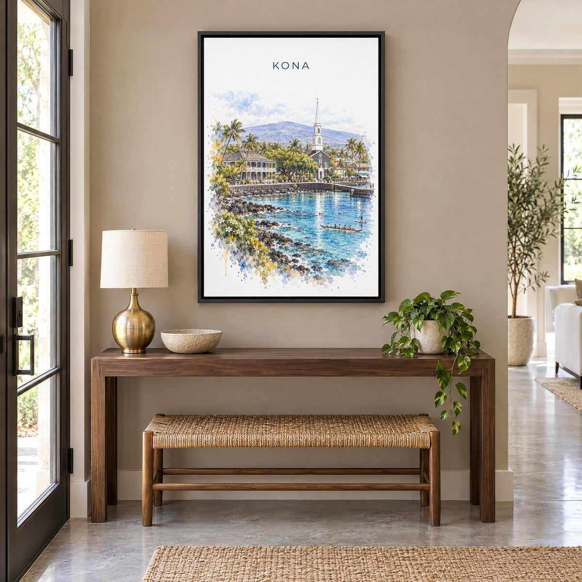 Kona, Hawaii watercolor print as a black floater canvas above a walnut console and woven bench in an entryway