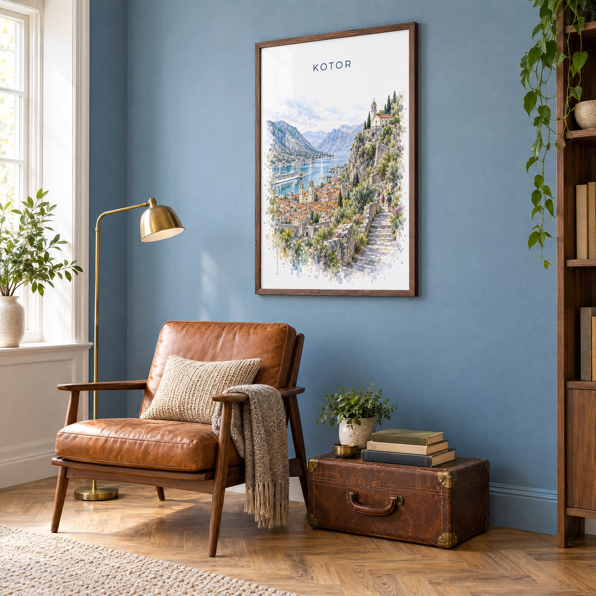 Kotor watercolor print in a walnut frame on a blue wall above a leather armchair in a reading nook