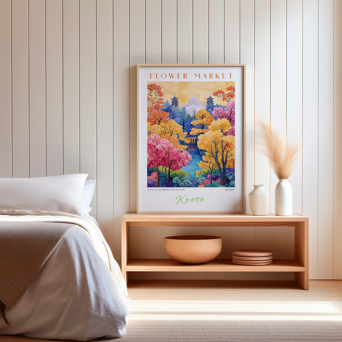 Kyoto flower market print in an oak frame on a wood bench against a white shiplap bedroom wall with pampas grass