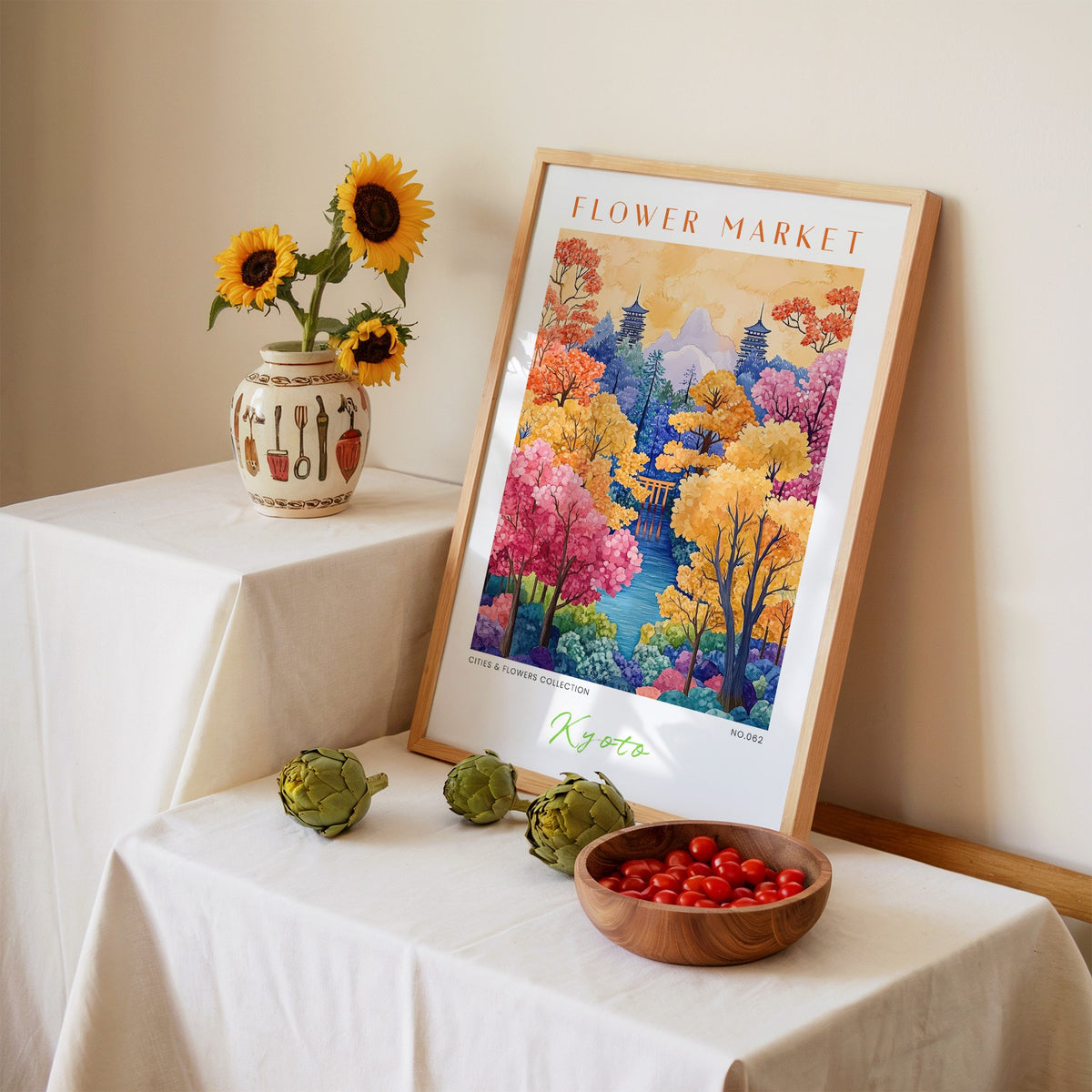 Kyoto flower market print in an oak frame leaning on a linen-draped table beside a vase of sunflowers