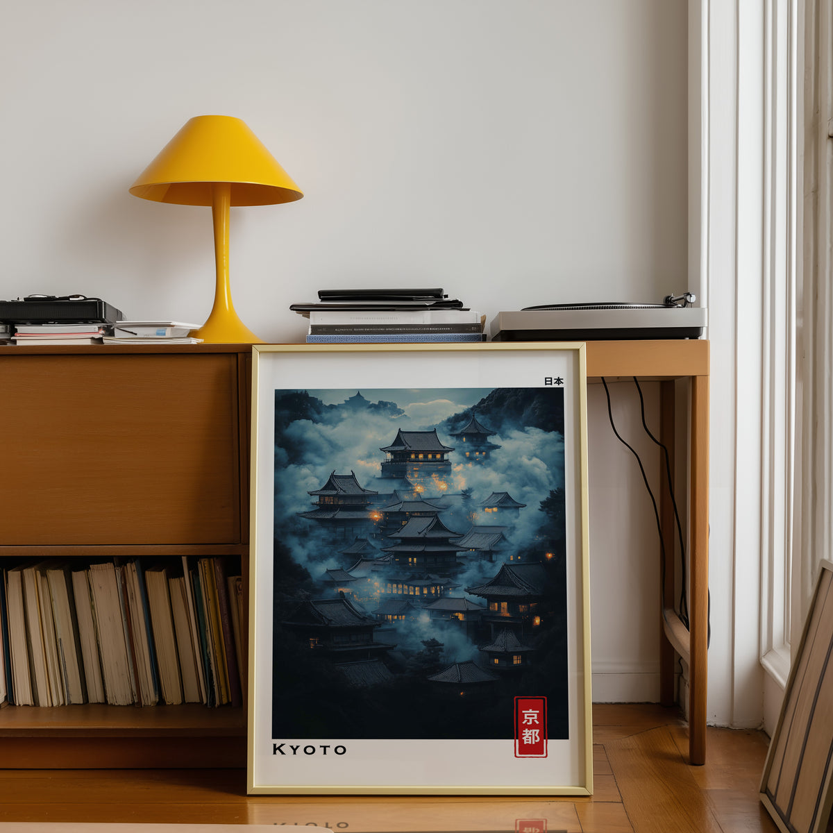 Kyoto misty night temples print shown in a gold frame below a teak desk with a yellow lamp