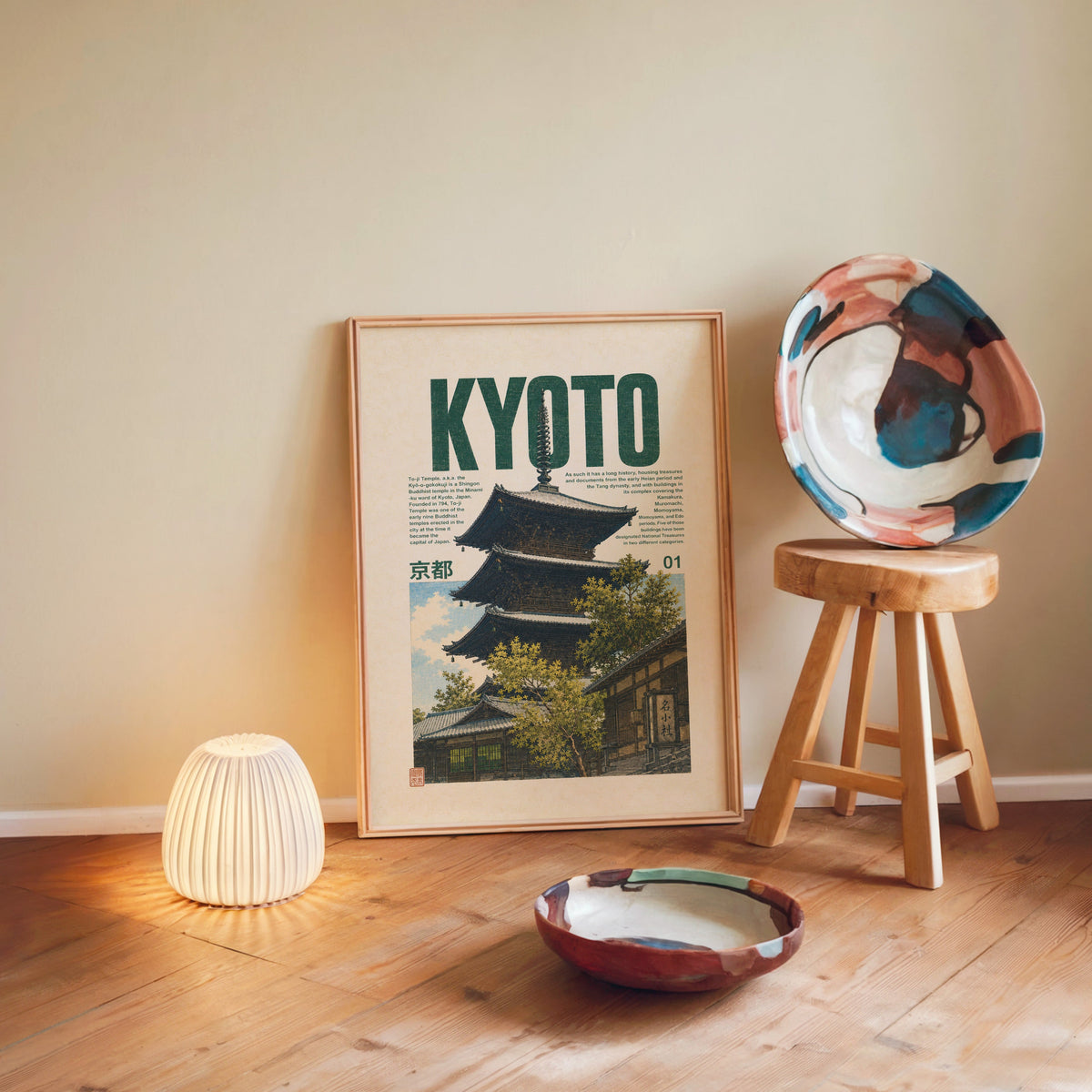Kyoto pagoda travel poster print in a light wood frame leaning on a wooden floor by a glowing lamp and stool