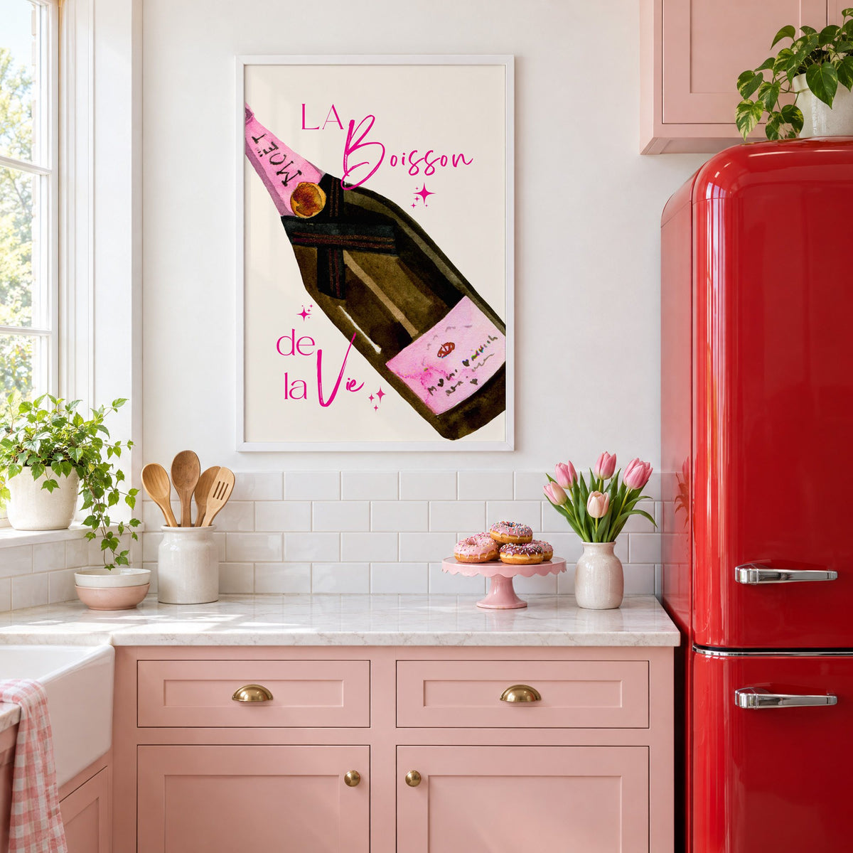 La Boisson champagne bottle watercolor print in a white frame in a pink kitchen beside a red retro fridge
