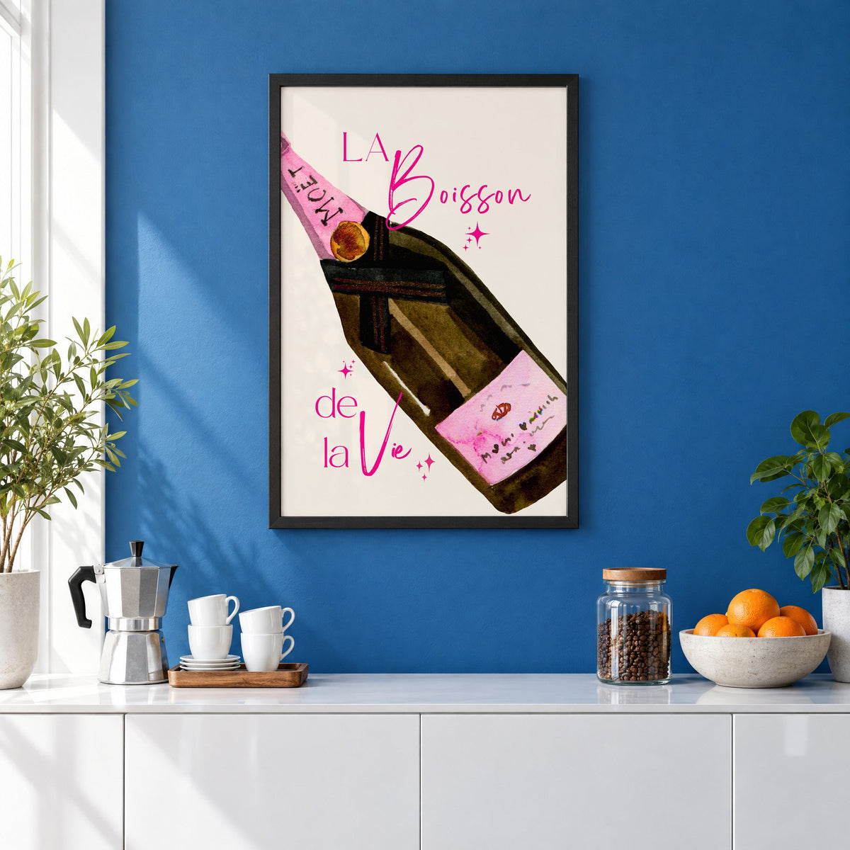 La Boisson champagne bottle watercolor print in a black frame on a cobalt blue wall above a coffee station