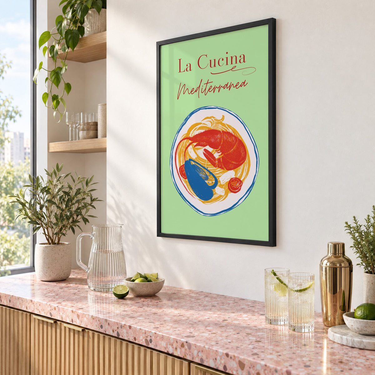 La Cucina Mediterranea seafood pasta print in a black frame above a pink terrazzo cocktail counter with limes, seen at an angle