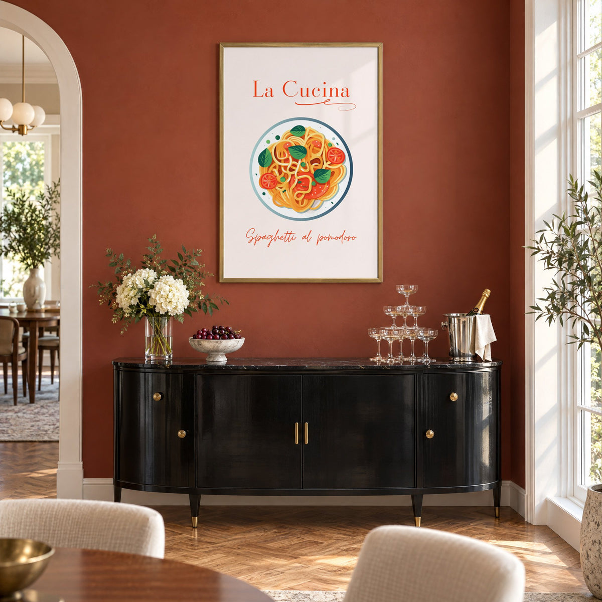 La Cucina spaghetti plate print in a brass frame on a terracotta wall above a black buffet with a champagne tower