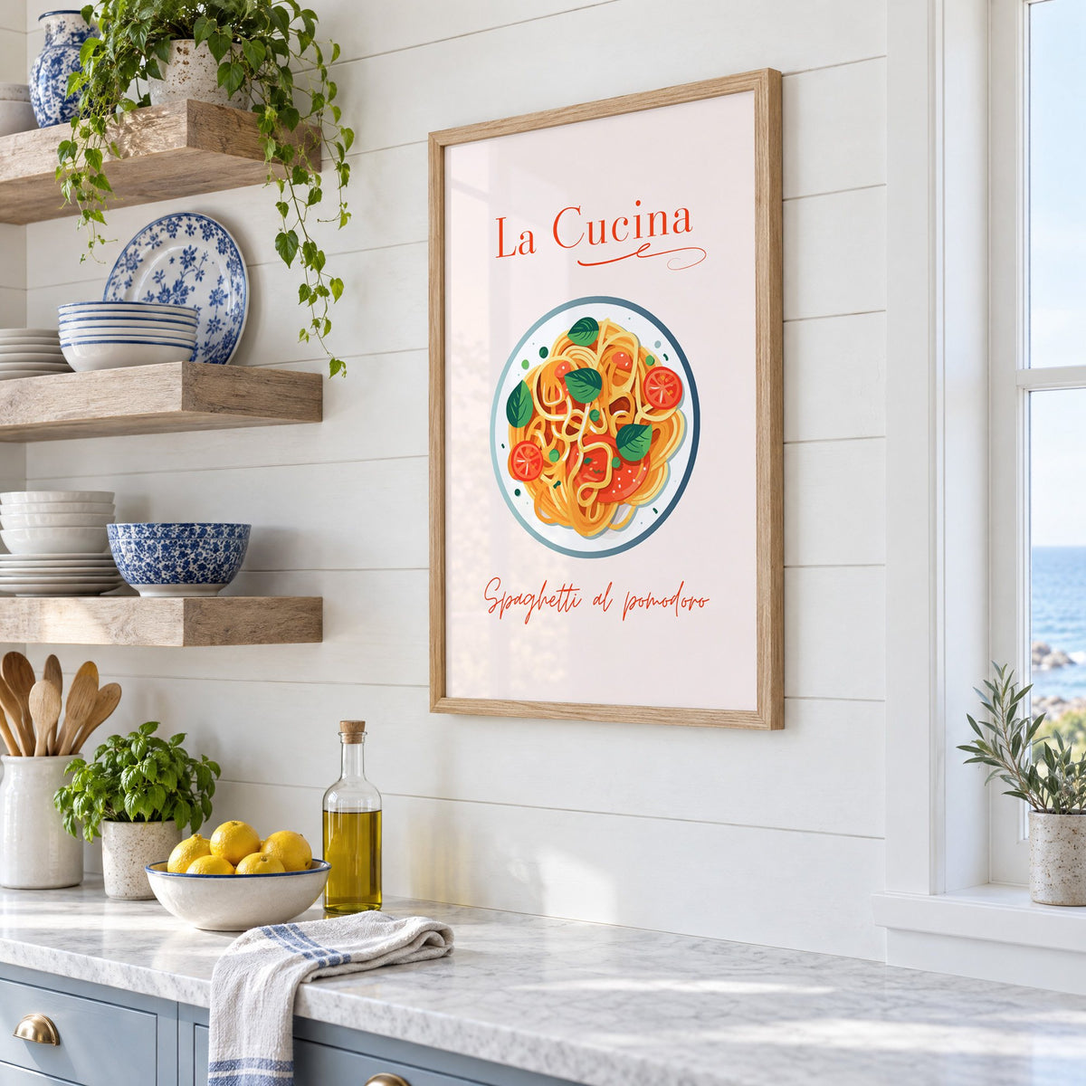 La Cucina spaghetti plate print in an oak frame in a white coastal kitchen beside blue and white plates
