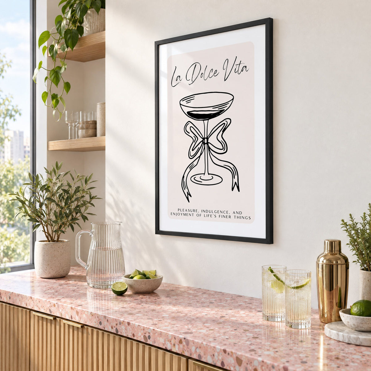 La Dolce Vita black line coupe print in a black frame above a pink terrazzo cocktail counter with limes, seen at an angle