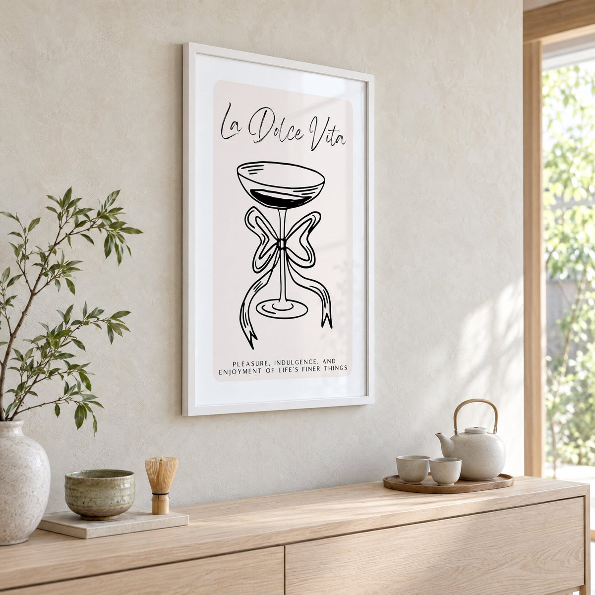 La Dolce Vita black line coupe print in a white frame above a pale wood console with a matcha tea set