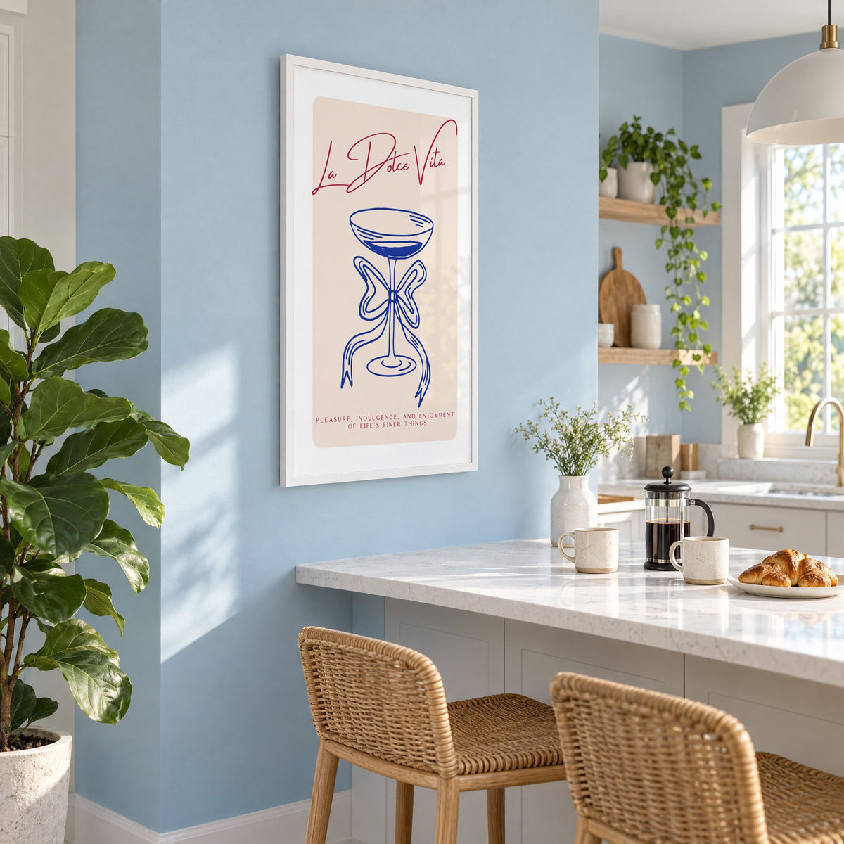 La Dolce Vita cobalt coupe print in a white frame on a pale blue wall above a breakfast bar with rattan stools