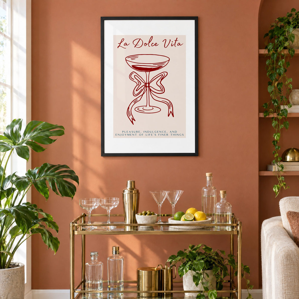 La Dolce Vita coupe bow line print in a black frame on a terracotta wall above a brass bar cart with coupes and citrus