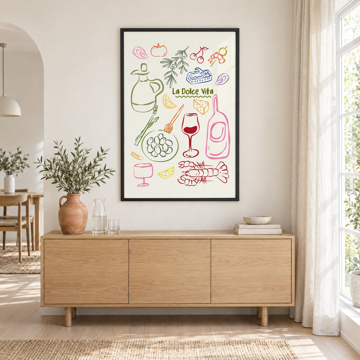 La Dolce Vita feast doodle print in a black frame above an oak sideboard with a terracotta vase of olive branches