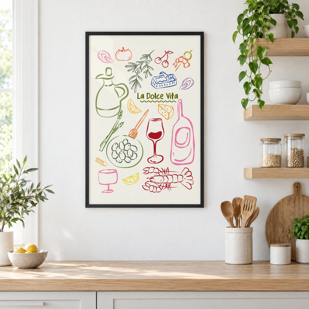 La Dolce Vita feast doodle print in a black frame in a white kitchen beside open wood shelves and glass jars
