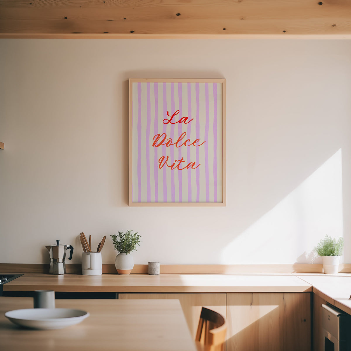 La Dolce Vita print in an oak frame above a wood counter with a moka pot and herbs