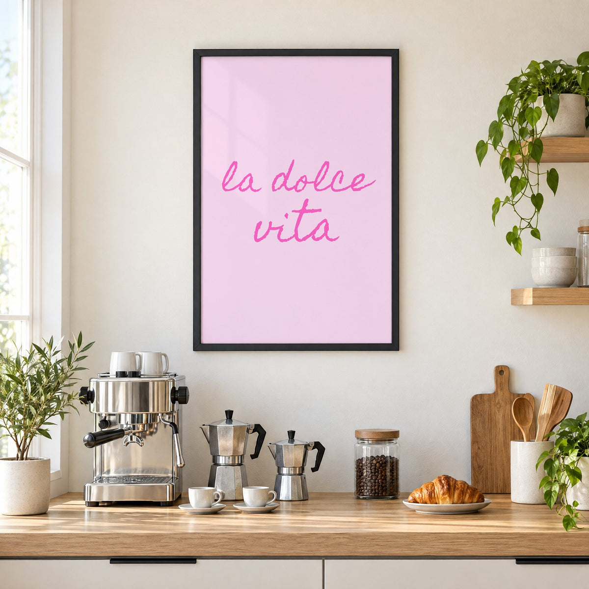 la dolce vita pink handwritten script print in a black frame above a home espresso bar with moka pots and espresso cups