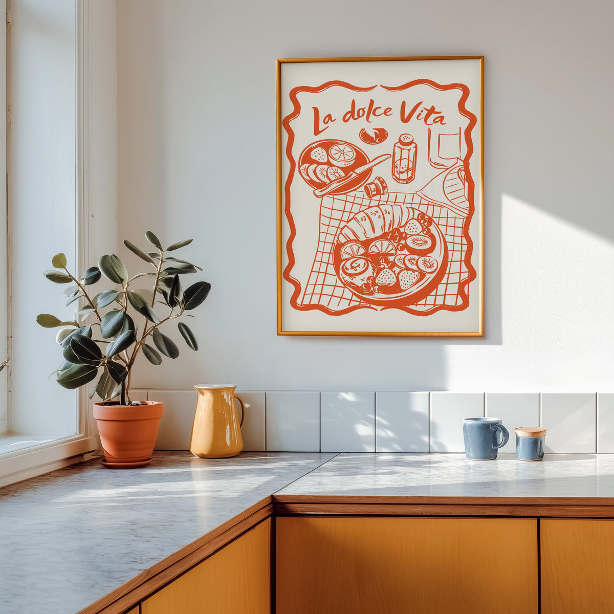 La Dolce Vita table print shown in a gold frame above a marble counter in a tan kitchen