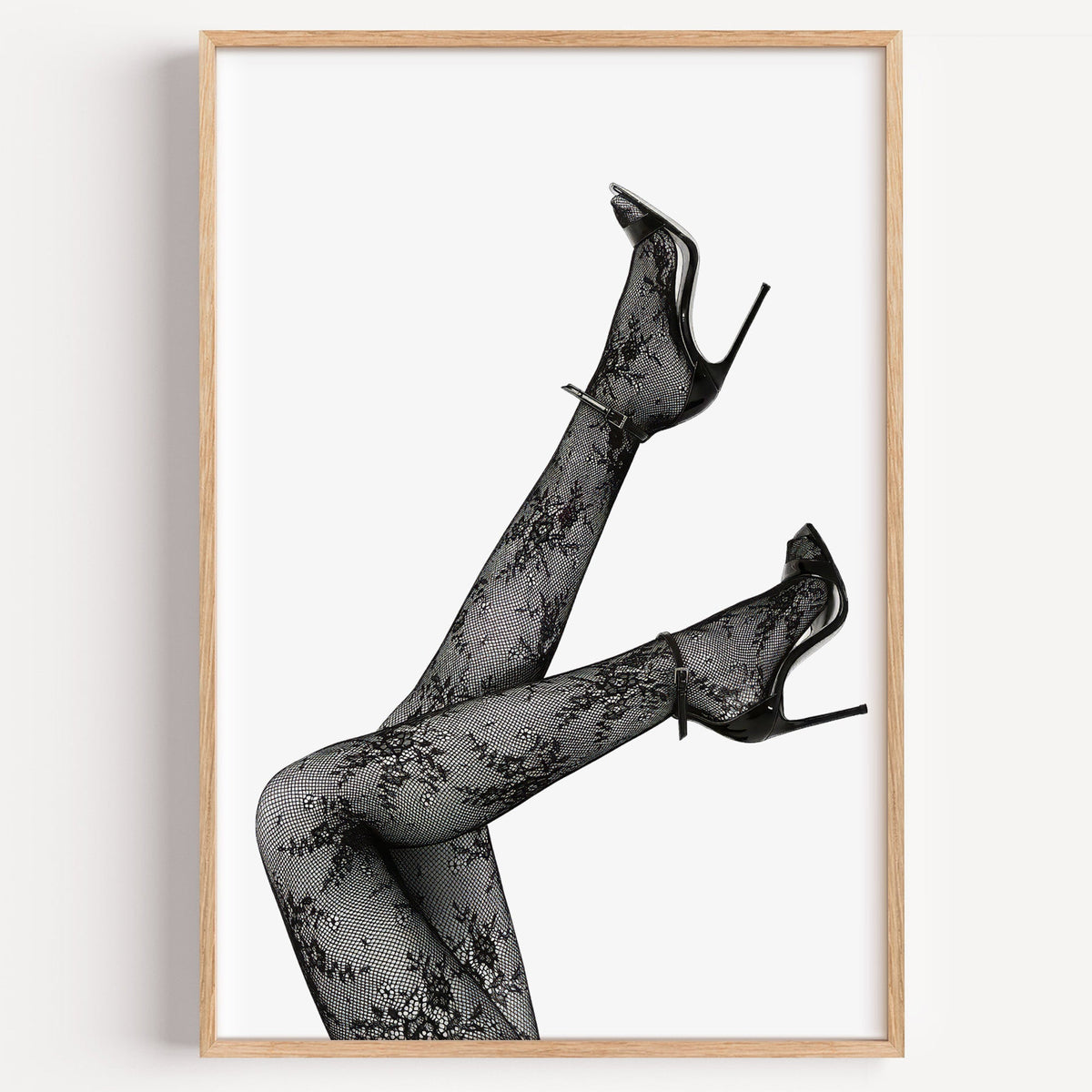 Legs in floral lace tights and stilettos print in a light oak frame on a plain white wall