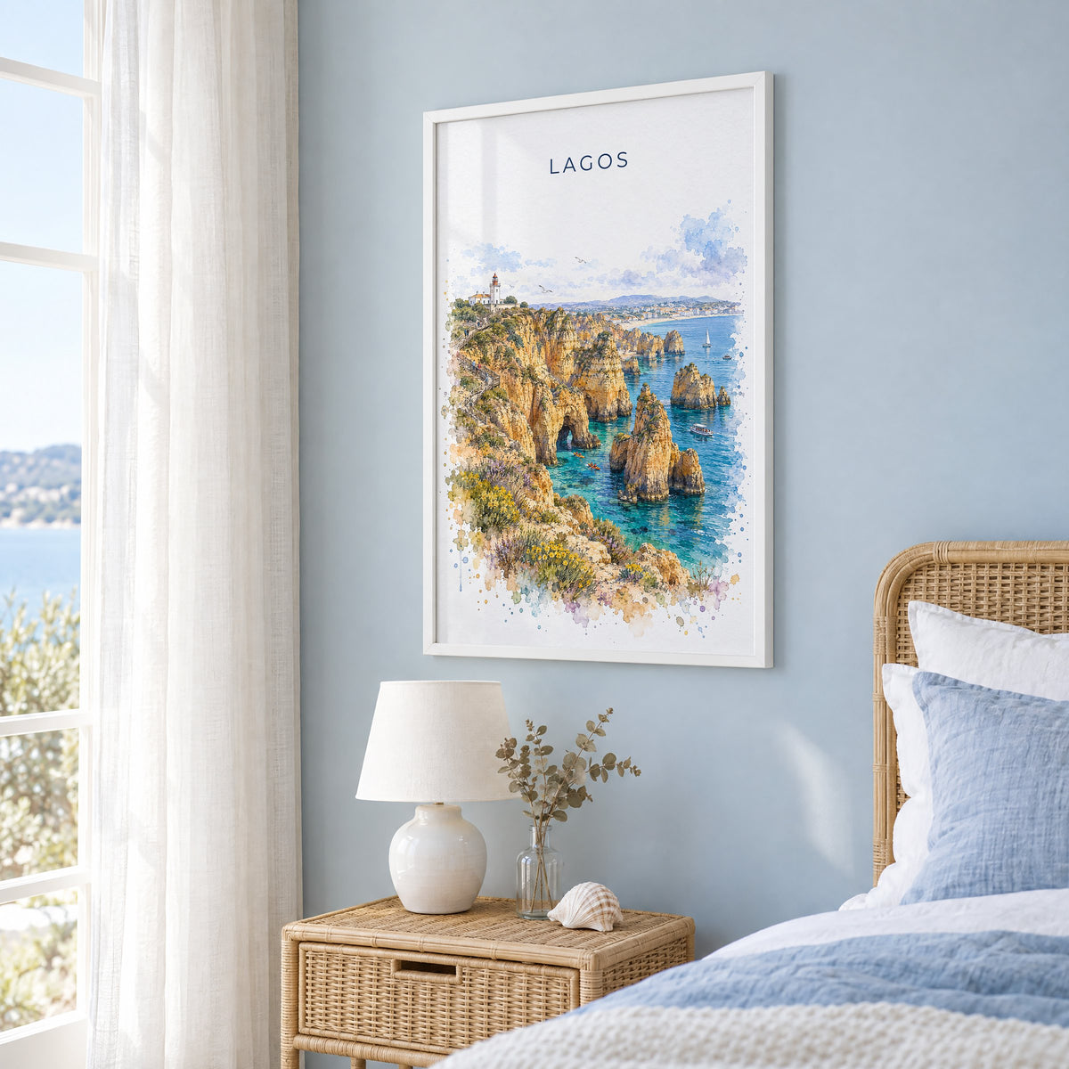 Lagos, Portugal watercolor print in a white frame on a pale blue wall beside a rattan bed in a coastal bedroom