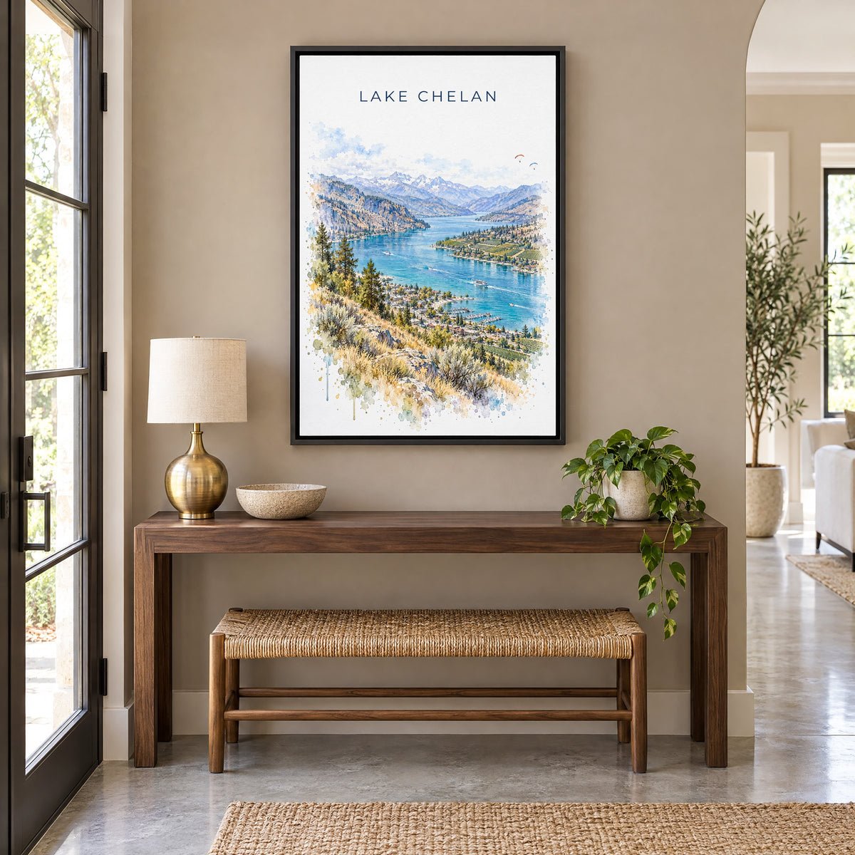 Lake Chelan watercolor print as a black floater canvas above a walnut console and woven bench in an entryway