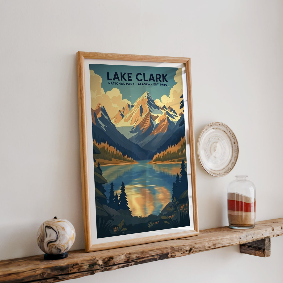 Lake Clark National Park print in an oak frame on a rustic wood shelf with ceramics and a sand-filled jar