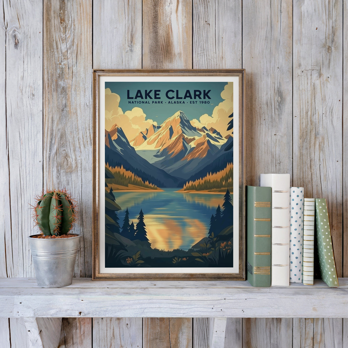 Lake Clark poster in an antique gold frame against whitewashed farmhouse planks beside books and a cactus