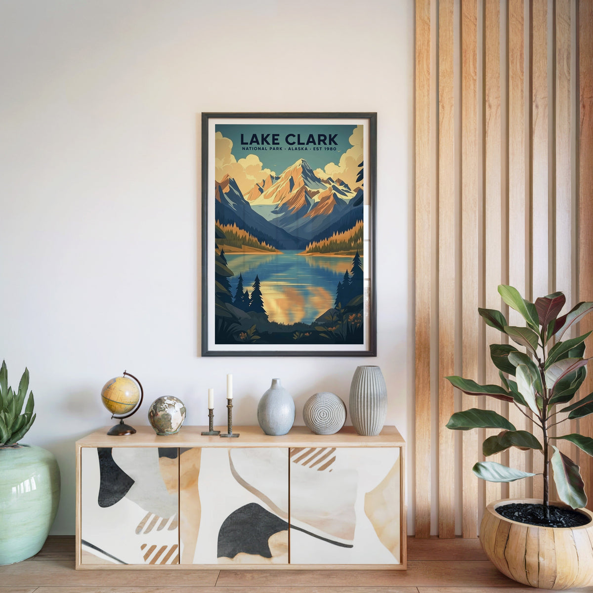 Lake Clark National Park print in a black frame above a light wood sideboard with a globe and ceramic vases
