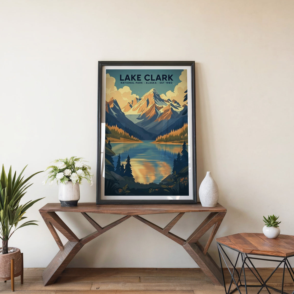 Lake Clark poster in a black frame on an entryway console table beside white flowers and a yucca