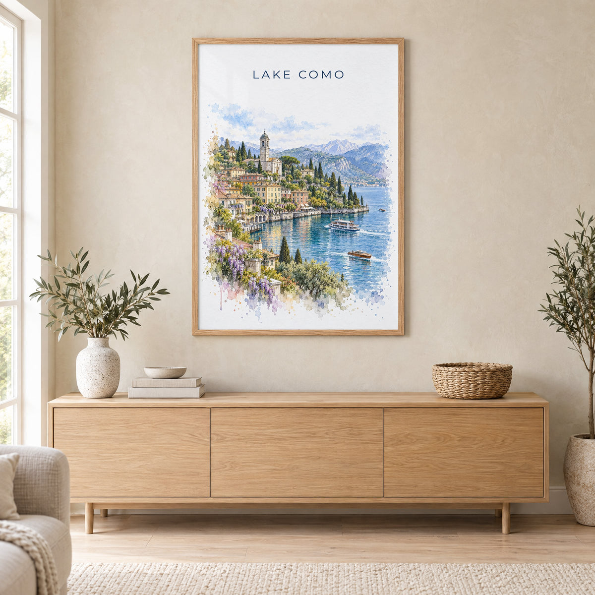 Lake Como watercolor print in an oak frame above a light wood sideboard in a Scandinavian living room