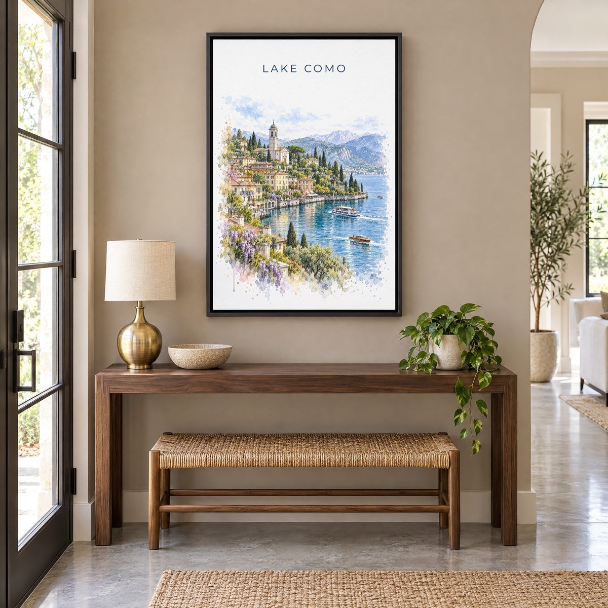 Lake Como watercolor print as a black floater canvas above a walnut console and woven bench in an entryway