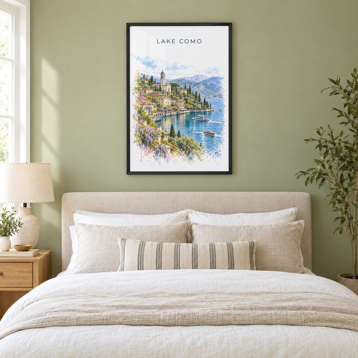 Lake Como watercolor print in a black frame above an upholstered headboard in a sage green bedroom