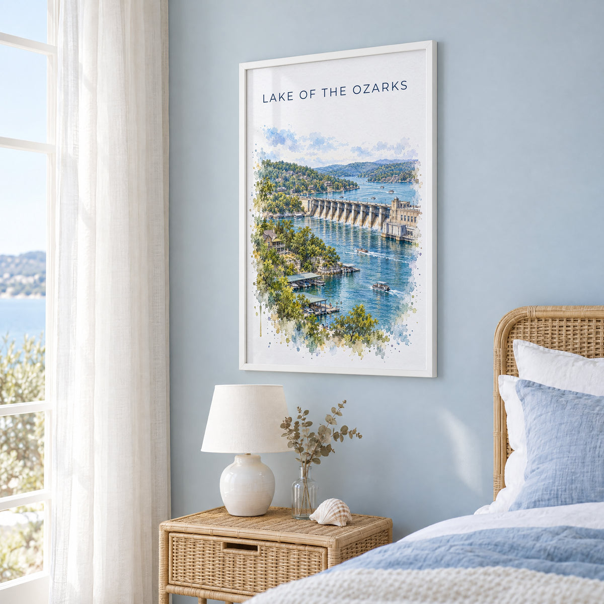 Lake of the Ozarks watercolor print in a white frame on a pale blue wall beside a rattan bed in a coastal bedroom