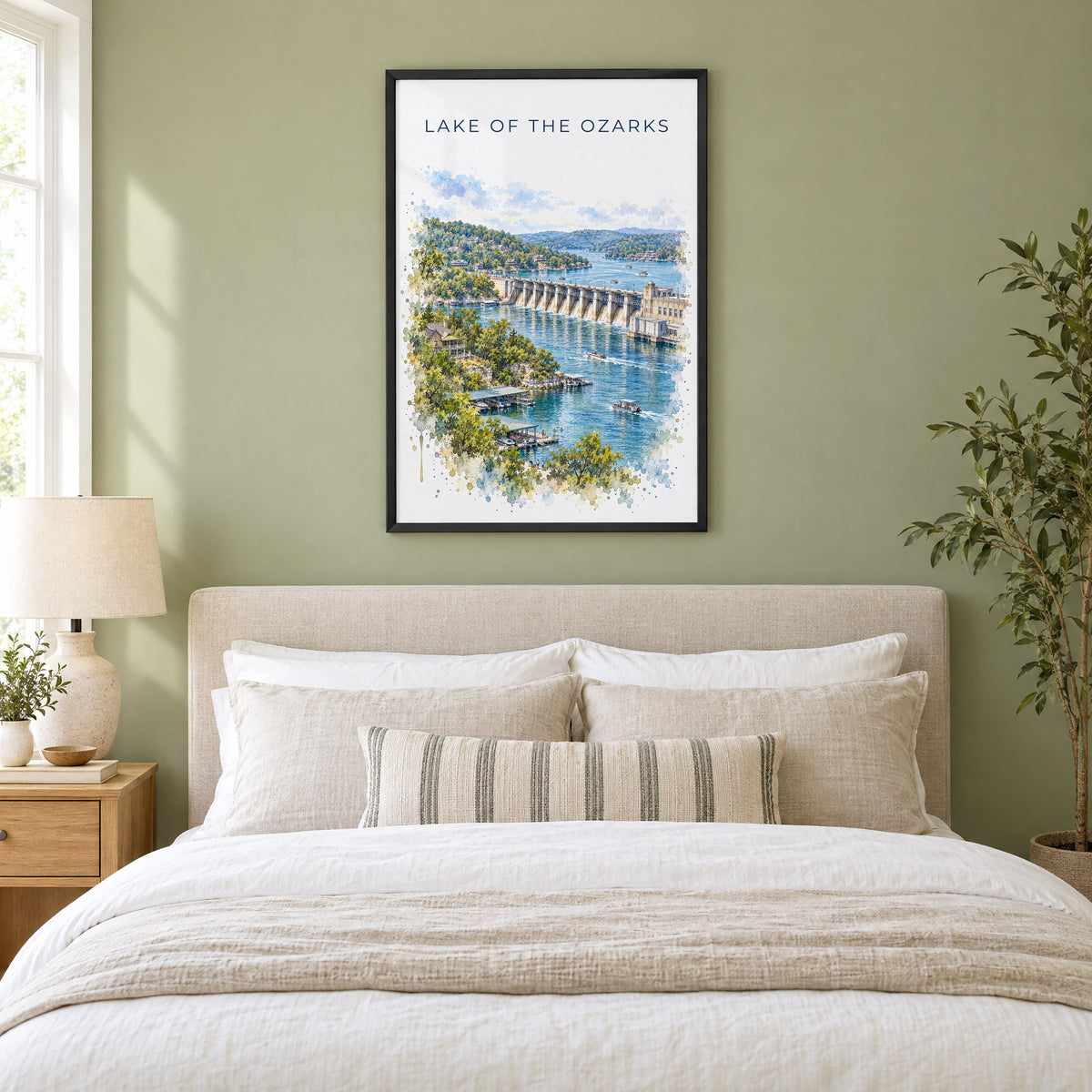 Lake of the Ozarks watercolor print in a black frame above an upholstered headboard in a sage green bedroom