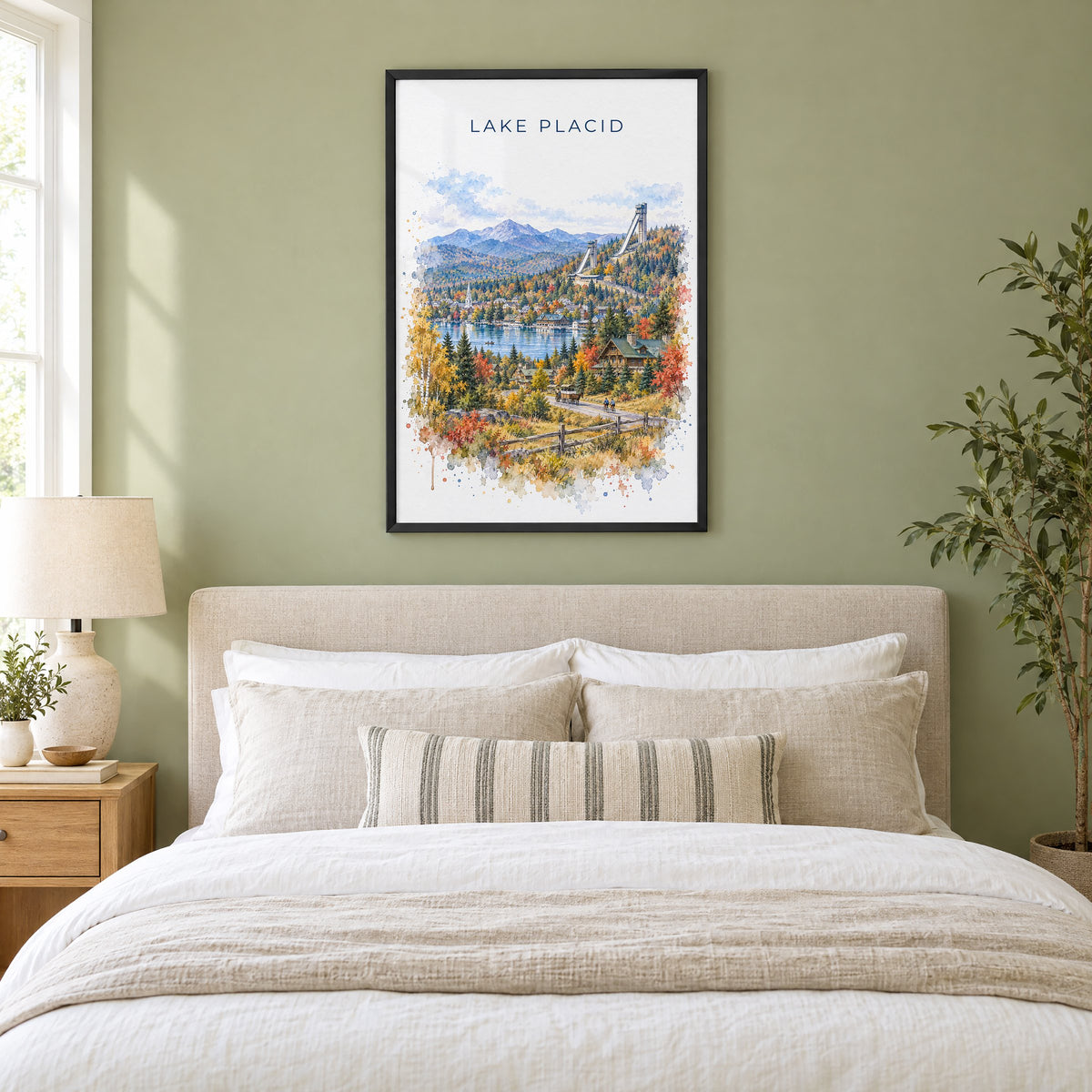 Lake Placid watercolor print in a black frame above an upholstered headboard in a sage green bedroom